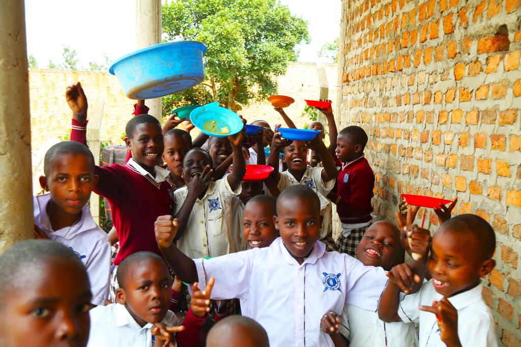 Pupils holding up bowls at a school feeding programme